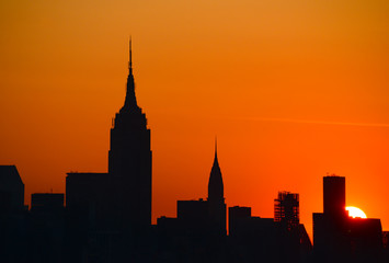 Fototapeta na wymiar Manhattan Wolkenkratzer Silhouetten Empire State Building Chrysler Building Sonnenaufgang Orange Sehenswürdigkeiten New Jersey Osten Sonne Feuerball