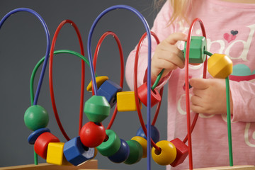 Toddler girl playing with wire bead maze toy. This colorful educational wooden toy teaches children...