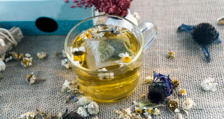 Glass cup and chamomile tea. Herbal slimming products on wicker background.