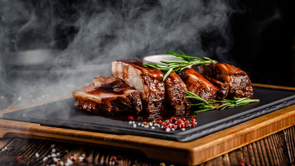 American food concept. Grilled pork ribs with grilled sauce, with smoke, spices and rosemary....