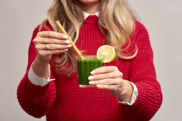 Woman holding fresh spinach green smoothie with bamboo straw