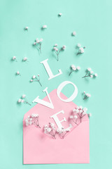 Flowers, pink envelope and word Love on a light green background