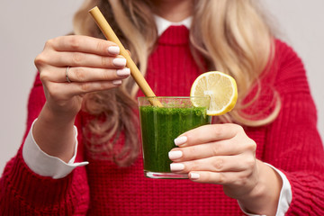 Woman holding fresh spinach green smoothie with bamboo straw