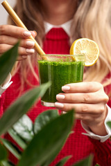 Woman holding fresh spinach green smoothie with bamboo straw