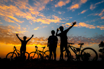 Family cyclist and Bicycle silhouettes on the dark background of sunsets