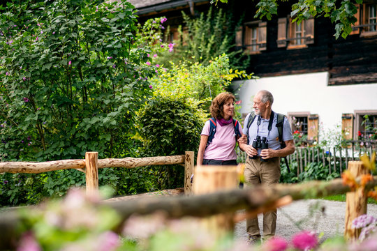 A senior pensioner couple with binoculars hiking, talking. - Powered by Adobe