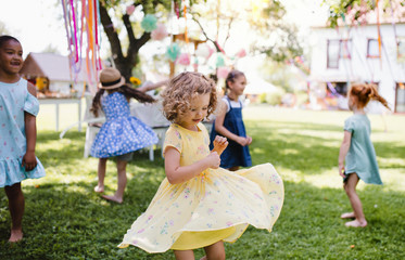 Small children standing outdoors in garden in summer, playing.