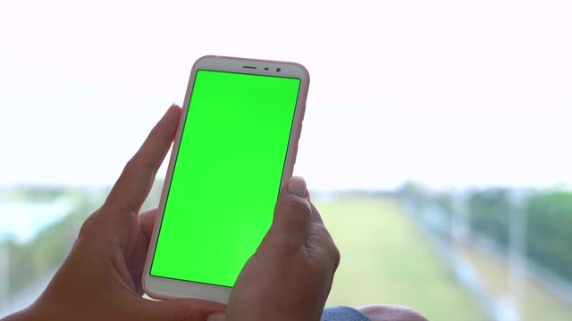 Closeup view of female hands holding smartphone with empty blank green screen. Woman browsing virtual and invisible pages of webside using touchscreen. Real time 4k video footage.