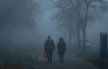 Old couple walking on street a foggy day