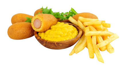 Mini party corn dogs on wooden sticks and French fries with a wooden bowl of American mustard isolated on a white background