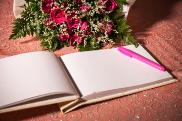 Fototapeta premium Wedding album, blank page, guest list, to do list.still life photography concept by memory and notebook.Red rose flower and Notepad book.Notebook and asters on canvas background.