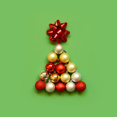 Christmas tree shape made with bauble on green background. Minimal holiday concept. Creative flat lay.
