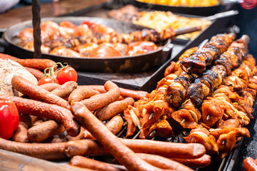 Roasted fat smoked and grilled pork legs, sausages, shashliks at christmas fair market.