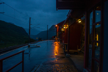 Fototapeta premium Cloudy evening on the street of empty train station. Completely alone. Rails and mountains are visible.