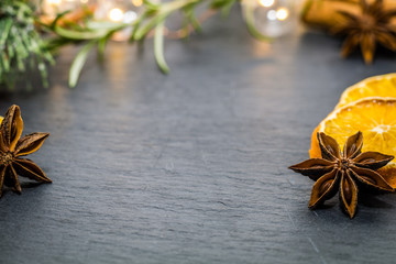 Winter holiday still life concept on dark slate board with dried oranges, anise stars, cinnamon...
