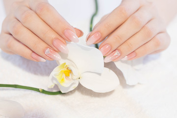 Obraz na płótnie Canvas Beautiful soft woman hands with light manicure hand care and spa relaxing white orchid