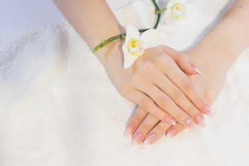 Beautiful soft woman hands with light manicure hand care and spa relaxing white orchid