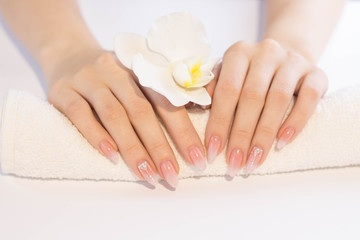 Beautiful soft woman hands with light manicure hand care and spa relaxing white orchid