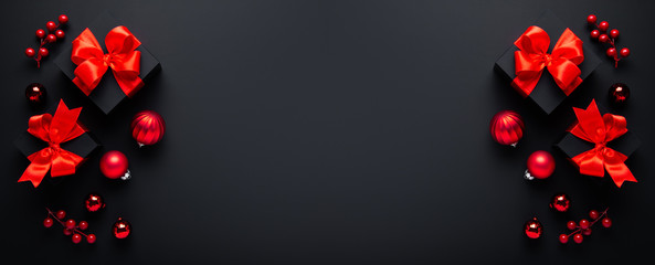 Merry Christmas and Happy Holidays greeting card, banner. New Year. Noel. Christmas red ornaments and gifts on black background top view. Winter xmas holiday theme.