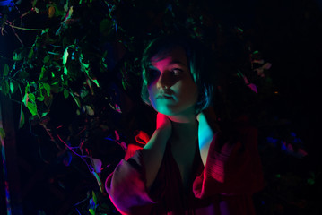 Young woman in the garden illuminated by multi-colored light.	