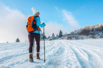 Happy woman tourist walking on the snowy trek on the peak of mou