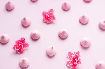 Small meringues and pink flowers on pink paper background. A pattern of small meringues and flowers. Gift for Valentine's Day.