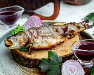 fried fish with chopped onions on a wooden hemp