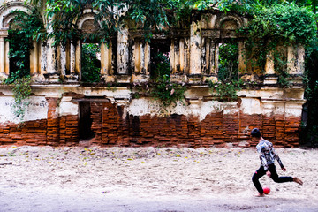 Niño a punto de chutar balon delante de edificio en runas (2) © Carles