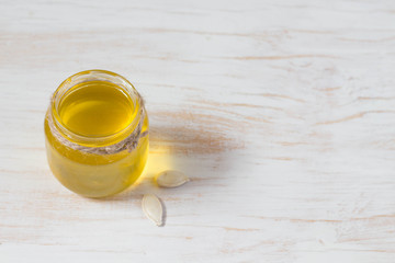Glass jar of pumpkin oil isolated on white with copy space