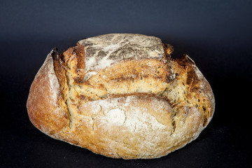 Loaf (or miche) of French sourdough, called as well as Pain de campagne, on display isolated on a black background. Pain de Campagne is a typical French huge loaf of bread abiding by traditional codes