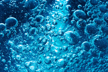 Sparkling Mineral Water Background. Blue bubbles of fresh soda float to the surface of drink to...