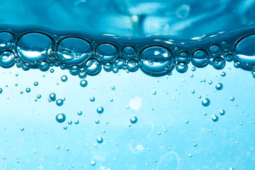 Sparkling Mineral Water Background. Blue bubbles of fresh soda float to the surface of drink to...