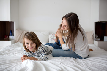 Mother, tickling her little boy, child giggling at home with mom