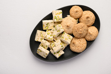 Nougat and almond cookies on a dark plate against a light background