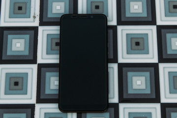 Mobile phone lying on a checkered background