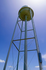 Tall Water tower with sun hiding behind with bright blue background and dark shadows