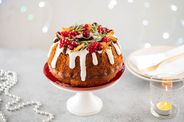 Traditional Christmas cake with fruits, nuts and white glazeon a light background with Christmas decorations. Copy space.