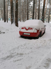 red car in the yard covered with snow