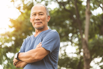 Naklejka na ściany i meble Asian Senior man in blue shirt smiling with arms crossed before exercising.