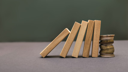 Wooden blocks with coins on a green background. Business concept