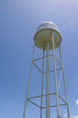 Tall Water tower with sun overhead with bright blue sky in background