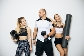 Young sports girls and boy are engaged in fitness, lifestyle, sports and healthy eating, in the gym girls do exercises,On a white background posing in a sports hall