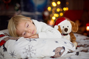 Sweet beautiful blond toddler boy, sleeping in bed with toy