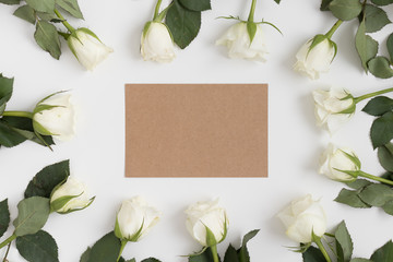 Top view of a kraft card mockup with roses on a white table.