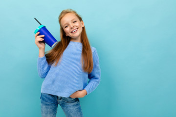 attractive european girl holding a glass in her hands on a light blue background