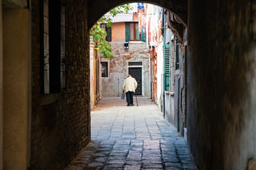 Fototapeta na wymiar Street life in Venice. Old woman walk in castello district