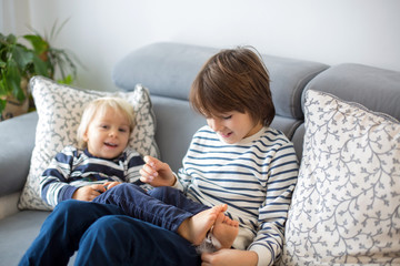 Little toddler and his older brother, having fun at home, tickling and giggle