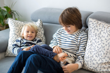 Little toddler and his older brother, having fun at home, tickling and giggle