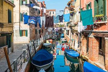 Fototapeta na wymiar Traditional canal street with reflection in the water laundry hanging out of a typical Venetian facade. Italy