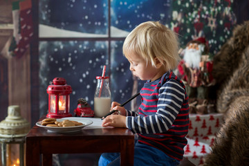 Sweet blonde toddler boy, writing letter to Santa, wishing presents